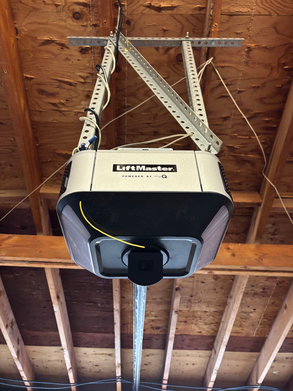 LiftMaster garage door opener mounted on ceiling with visible electrical wiring and support brackets.