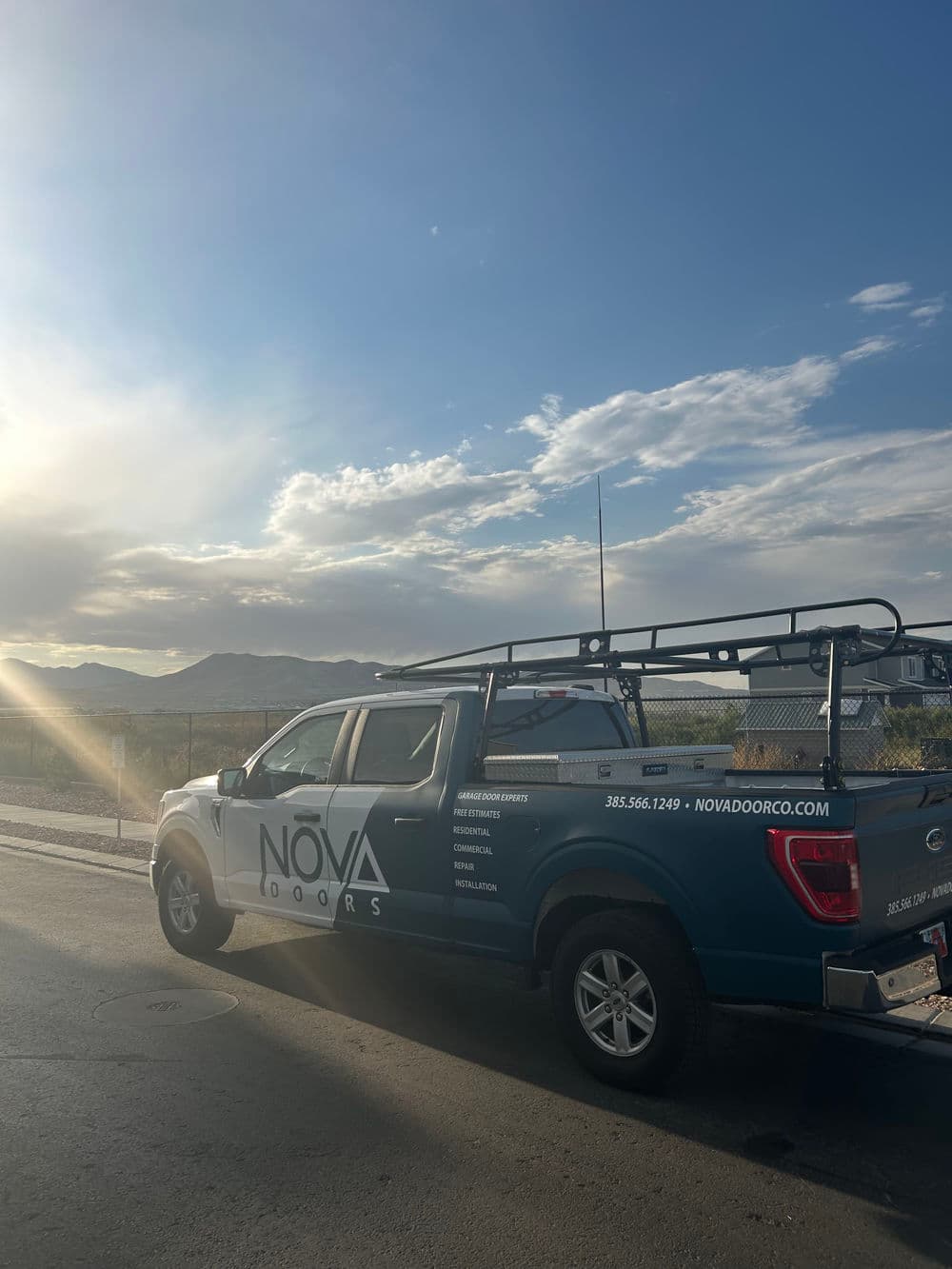 Nova Doors branded truck parked with mountains and cloudy sky in the background.