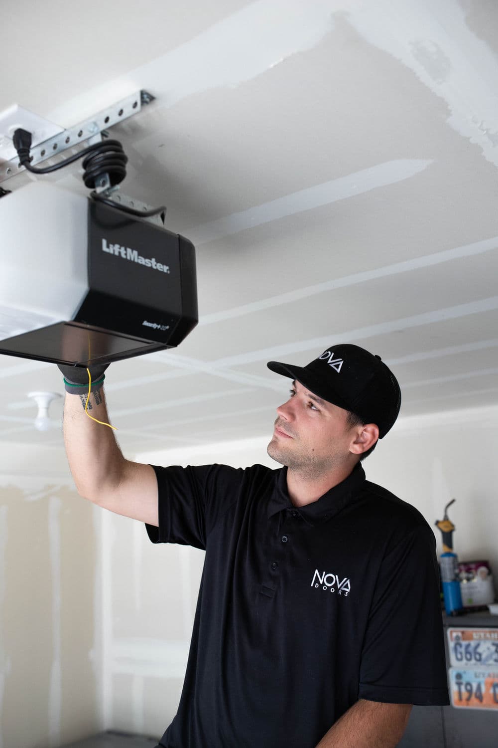 Technician installing LiftMaster garage door opener in residential garage.