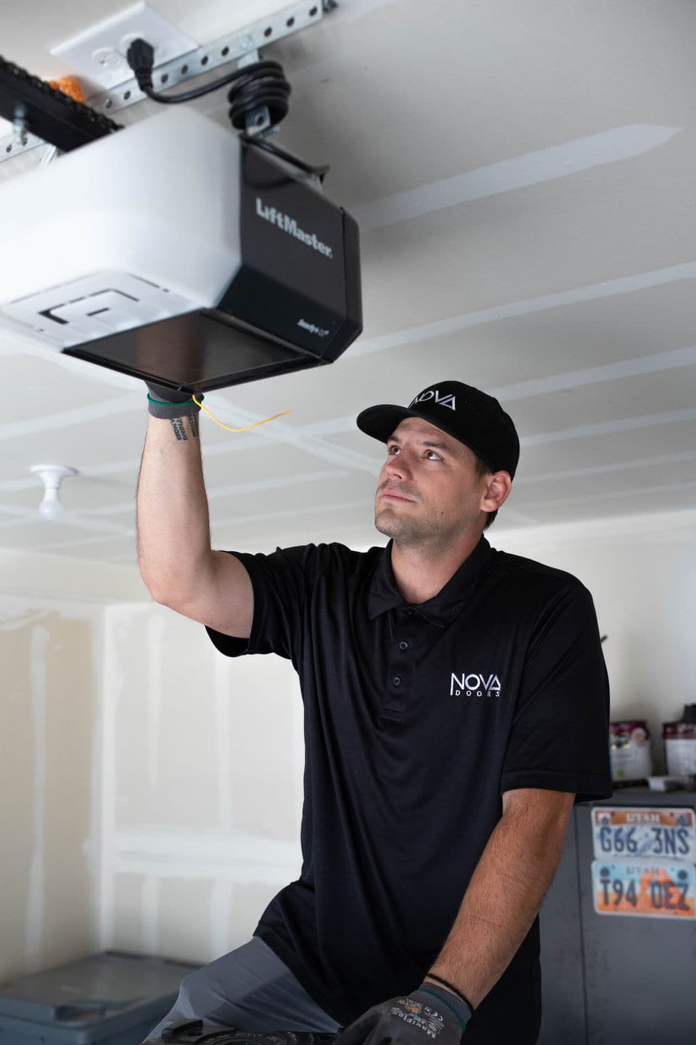 Technician installing a LiftMaster garage door opener in a residential garage.