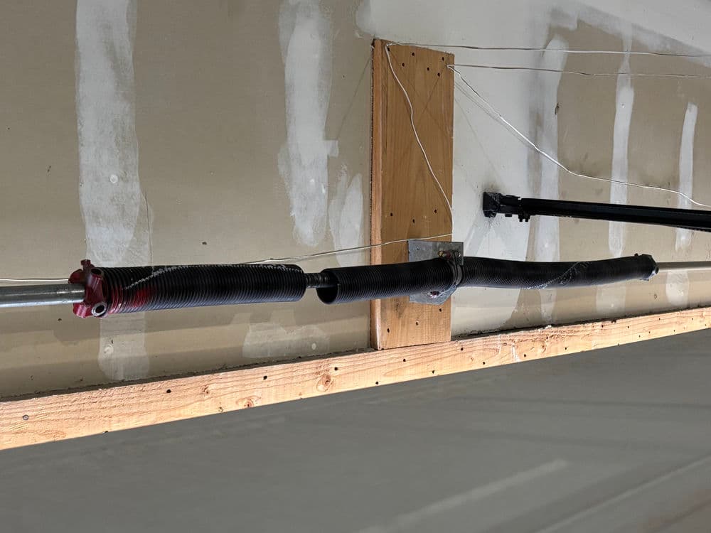 Garage door spring system installed on wall, showing cables and pulleys for operation.